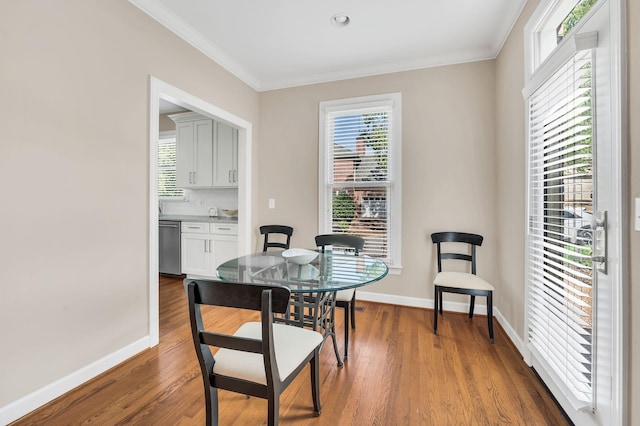 dining room with ornamental molding, wood finished floors, and baseboards