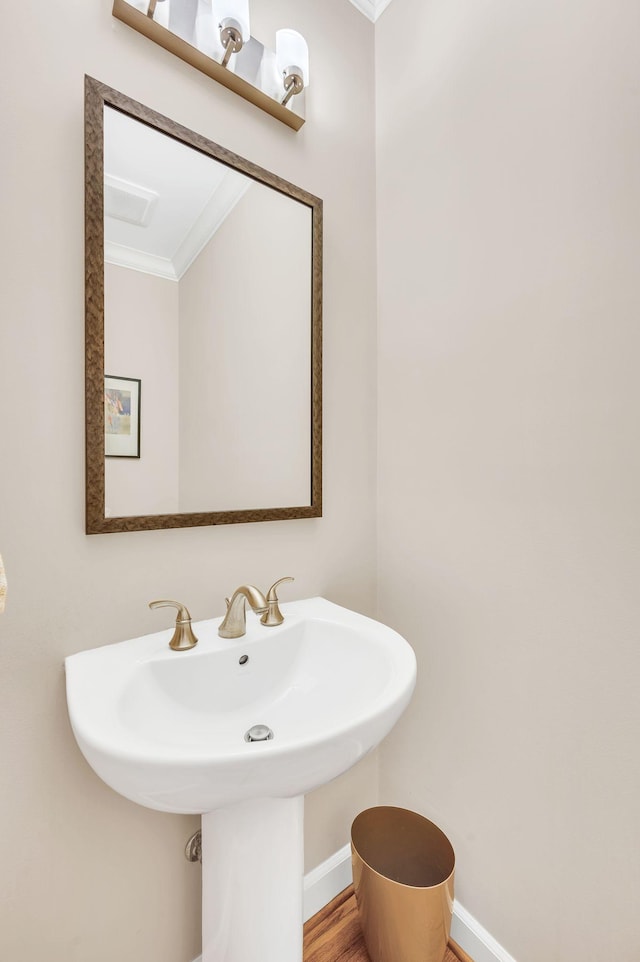 bathroom featuring a sink, baseboards, ornamental molding, and wood finished floors