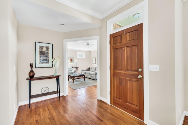 foyer entrance featuring ornamental molding, baseboards, and wood finished floors