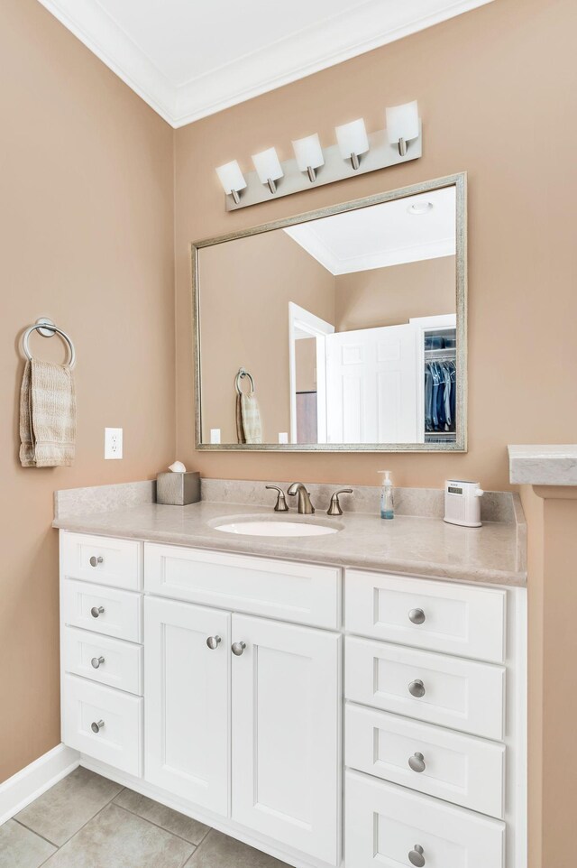 bathroom with vanity, baseboards, ornamental molding, tile patterned floors, and a walk in closet