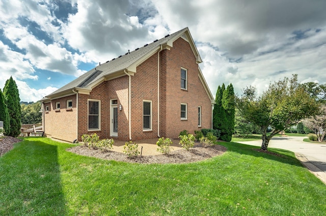 view of side of home with a lawn and brick siding