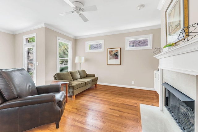 living room featuring crown molding, baseboards, a fireplace with flush hearth, and light wood-style floors