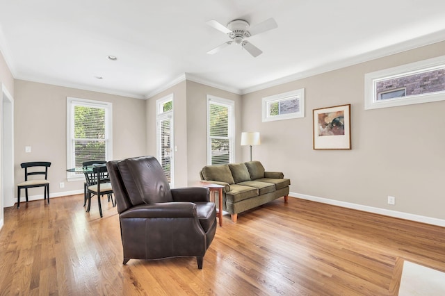 living room with crown molding, ceiling fan, light wood finished floors, and baseboards