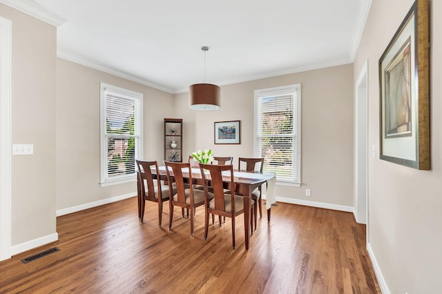 dining area featuring a healthy amount of sunlight, crown molding, visible vents, and wood finished floors