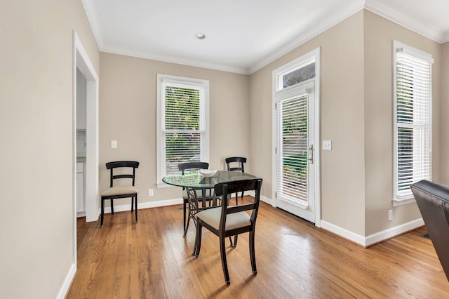 dining space featuring ornamental molding, a healthy amount of sunlight, light wood-style flooring, and baseboards