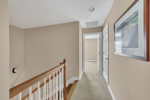 hallway with baseboards, visible vents, carpet flooring, and an upstairs landing