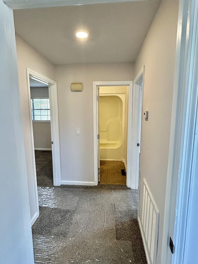 hall featuring baseboards and visible vents