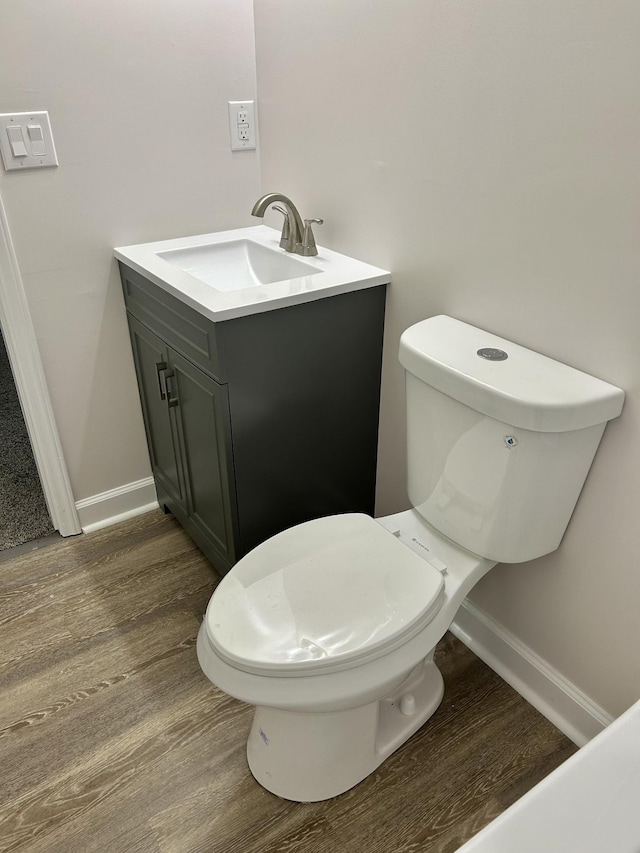 bathroom with toilet, baseboards, wood finished floors, and vanity