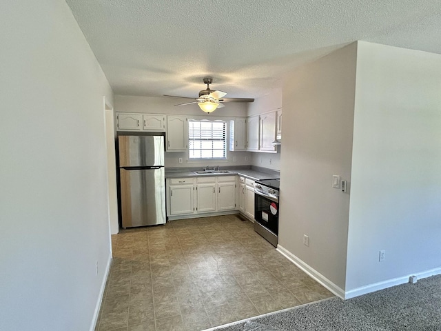 kitchen with appliances with stainless steel finishes, white cabinetry, a sink, and baseboards