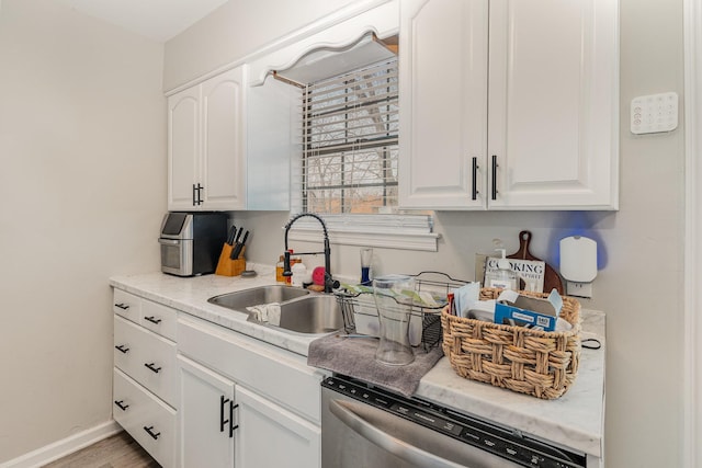 kitchen featuring baseboards, white cabinetry, a sink, and dishwasher