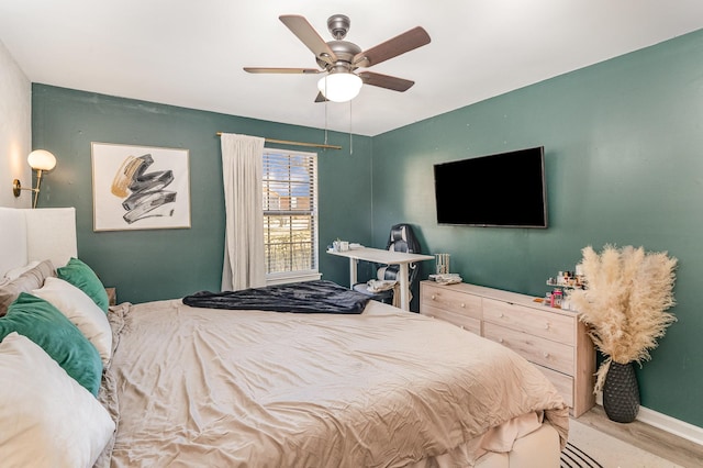 bedroom featuring ceiling fan, baseboards, and wood finished floors