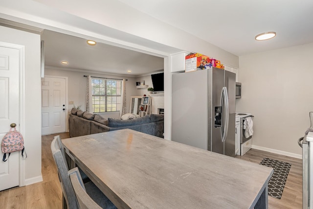 kitchen with stainless steel appliances, light wood finished floors, a brick fireplace, and baseboards