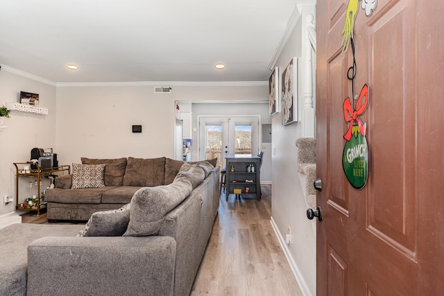 living area with light wood-style flooring, visible vents, baseboards, ornamental molding, and french doors