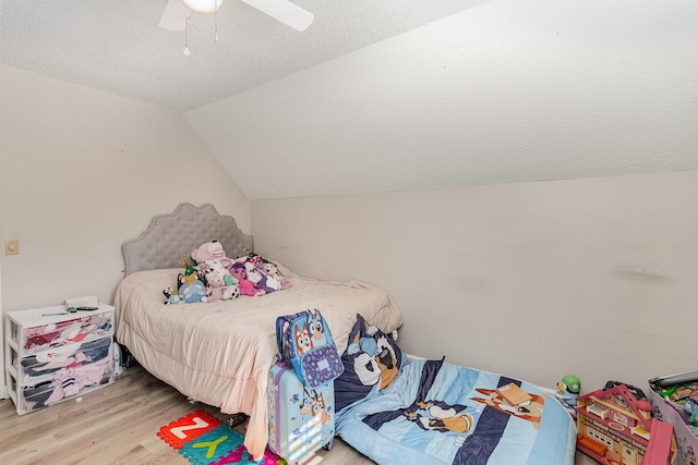 bedroom with vaulted ceiling, ceiling fan, a textured ceiling, and wood finished floors