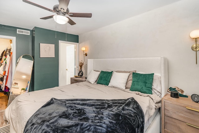 bedroom with wood finished floors, visible vents, a ceiling fan, a spacious closet, and a closet