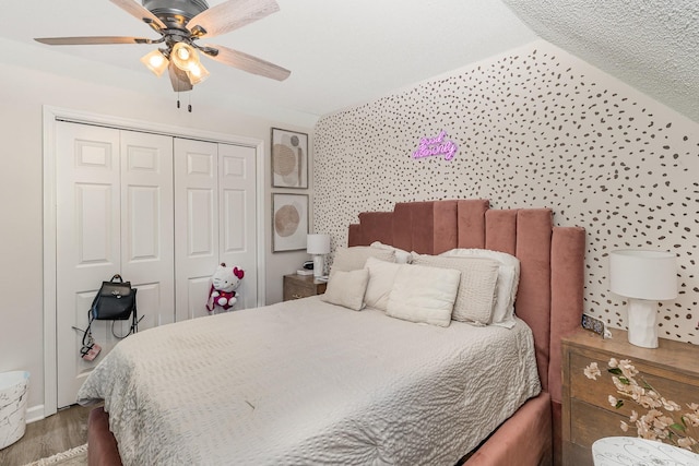 bedroom with lofted ceiling, a ceiling fan, a closet, and wood finished floors