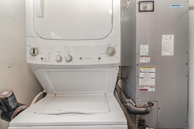 laundry area featuring heating unit, stacked washer and dryer, and laundry area