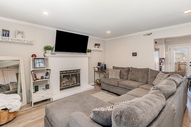 living area with visible vents, ornamental molding, light wood-style floors, a fireplace, and recessed lighting