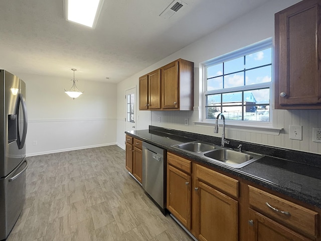 kitchen with dark countertops, visible vents, stainless steel appliances, and a sink