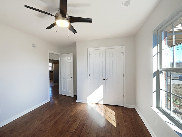 unfurnished bedroom featuring dark wood-style floors, multiple windows, visible vents, and baseboards