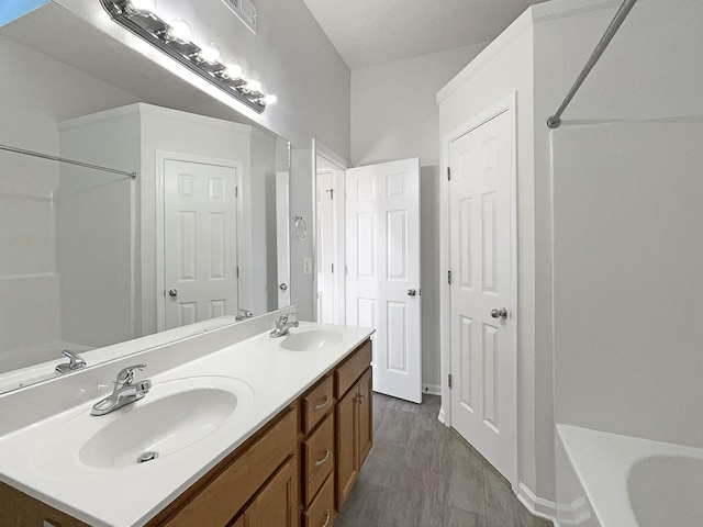 bathroom with a tub to relax in, a sink, and double vanity