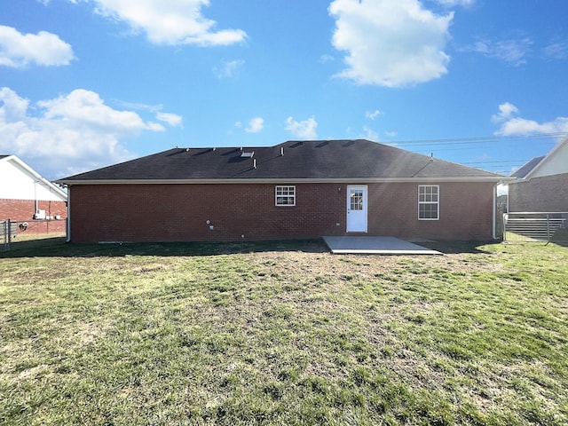 rear view of property featuring brick siding, a yard, and fence