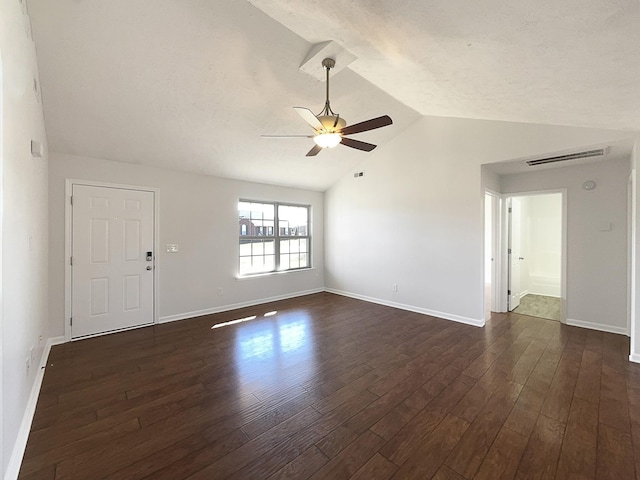 empty room featuring lofted ceiling, visible vents, dark wood-type flooring, ceiling fan, and baseboards