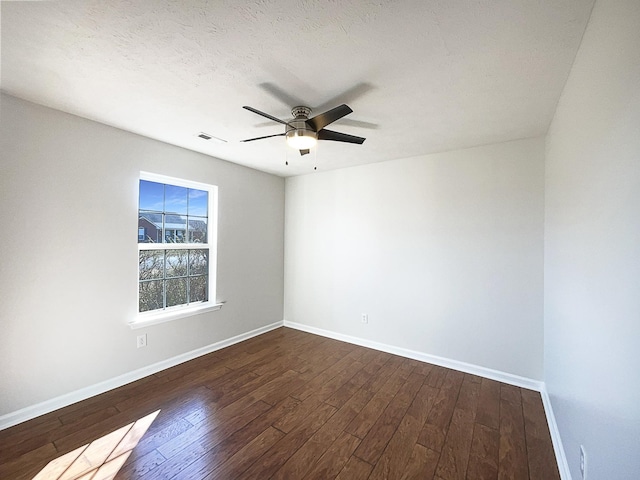 unfurnished room with dark wood-style flooring, visible vents, a textured ceiling, and baseboards