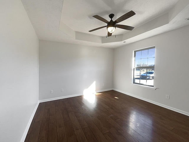 unfurnished room with visible vents, baseboards, a raised ceiling, ceiling fan, and hardwood / wood-style floors