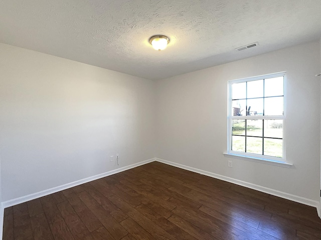 unfurnished room with a textured ceiling, dark wood-style flooring, visible vents, and baseboards