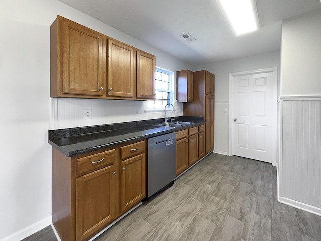 kitchen with dark countertops, visible vents, brown cabinetry, a sink, and dishwasher