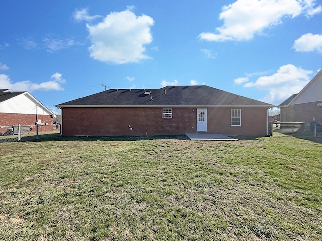 back of property featuring brick siding, fence, a lawn, a gate, and a patio area