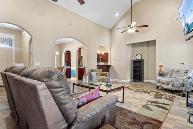 living room featuring arched walkways, ceiling fan, high vaulted ceiling, wood finished floors, and baseboards