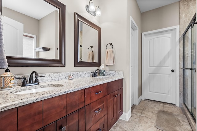 full bathroom featuring double vanity, a stall shower, baseboards, and a sink