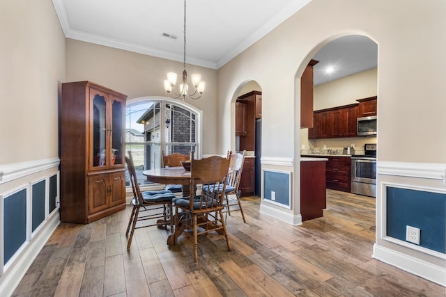 dining space with arched walkways, visible vents, a chandelier, and wood finished floors