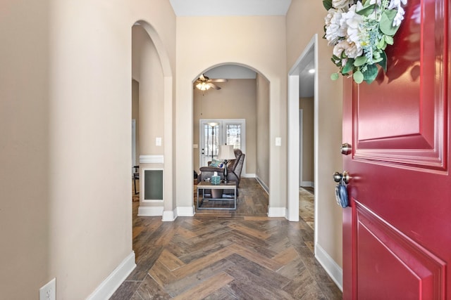 foyer with arched walkways, ceiling fan, and baseboards