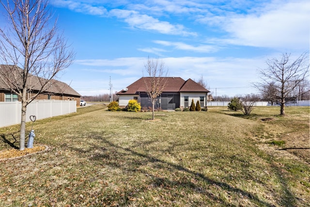 back of property featuring fence and a yard