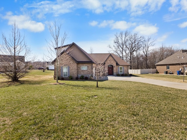 view of front of property featuring a front yard, brick siding, fence, and driveway