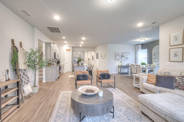 living area with recessed lighting, visible vents, and light wood finished floors