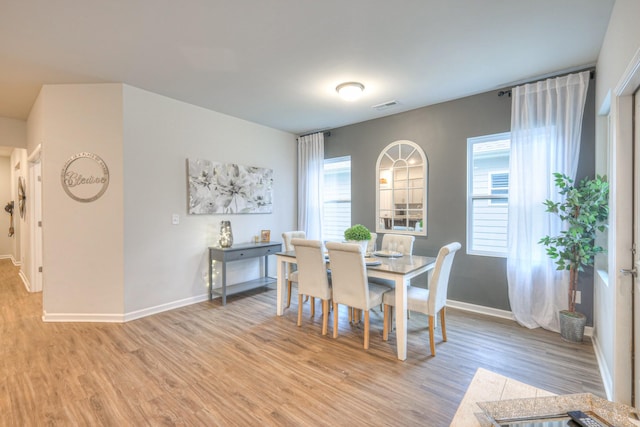 dining space featuring light wood-type flooring, visible vents, and baseboards