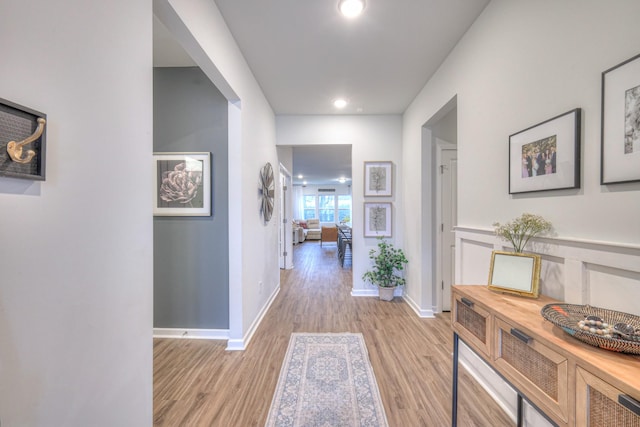 hall with light wood-style floors, baseboards, and recessed lighting