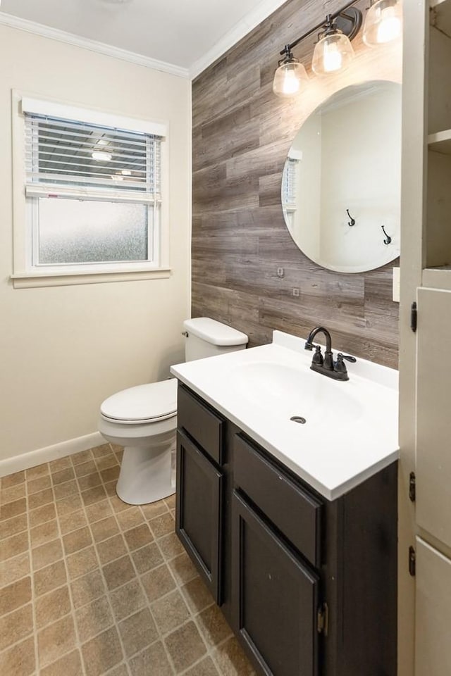 bathroom featuring toilet, wooden walls, vanity, baseboards, and ornamental molding