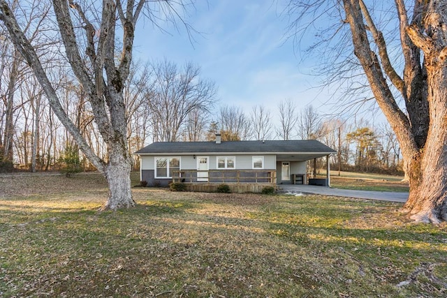 view of front of property featuring a front yard, a chimney, driveway, and an attached carport