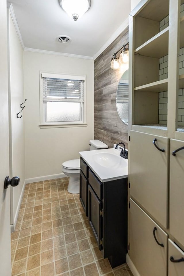 bathroom featuring toilet, ornamental molding, visible vents, and wooden walls