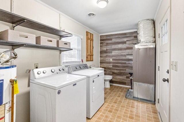 washroom with electric water heater, wooden walls, laundry area, visible vents, and washer and dryer