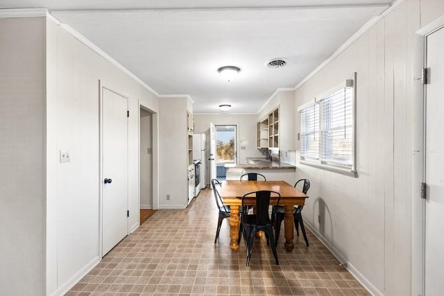 dining room with baseboards, visible vents, and crown molding