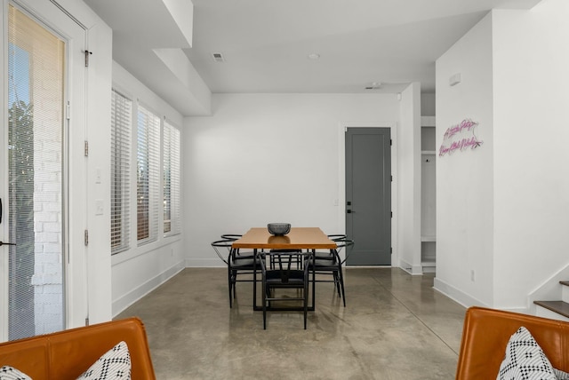 dining room with visible vents, finished concrete floors, baseboards, and stairs