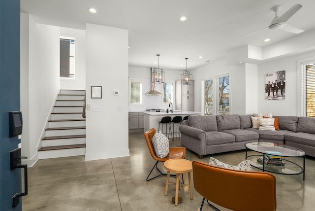 living area featuring recessed lighting, stairway, a ceiling fan, concrete flooring, and baseboards