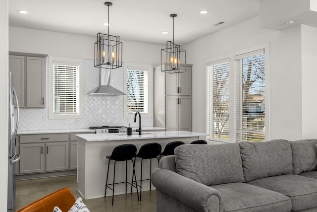 kitchen featuring gray cabinetry, visible vents, open floor plan, freestanding refrigerator, and wall chimney exhaust hood