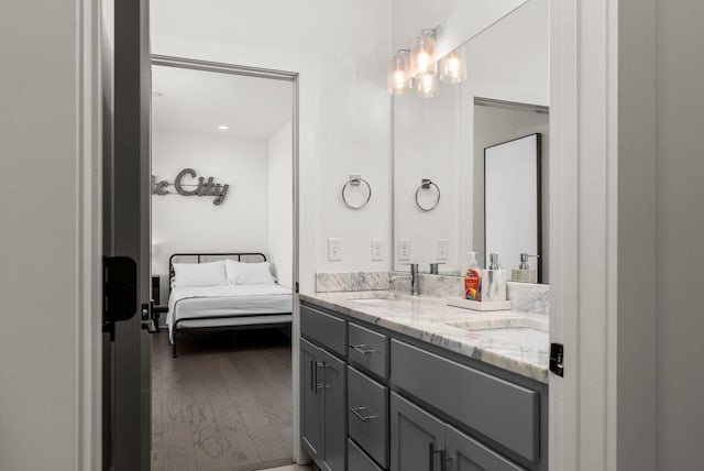 bathroom with double vanity, connected bathroom, a sink, and wood finished floors